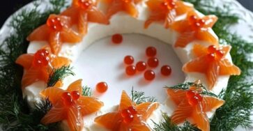 Couronne festive au fromage et saumon fumé, décorée avec œufs de saumon, aneth et crackers autour.