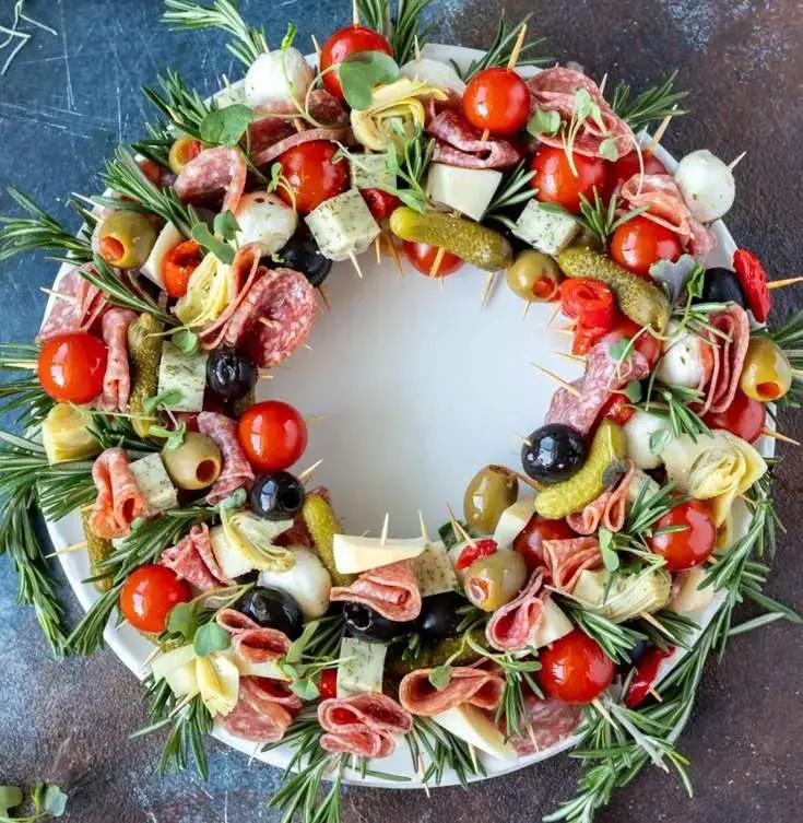 Couronne apéritive festive décorée d'olives, légumes marinés et fromages.