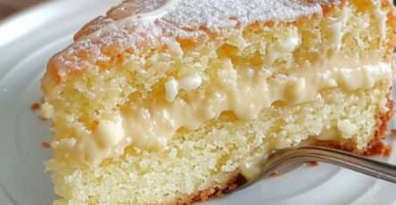 Gâteau blanc moelleux avec un glaçage doré au sucre à la crème, servi sur une assiette élégante avec une tasse de thé en arrière-plan.