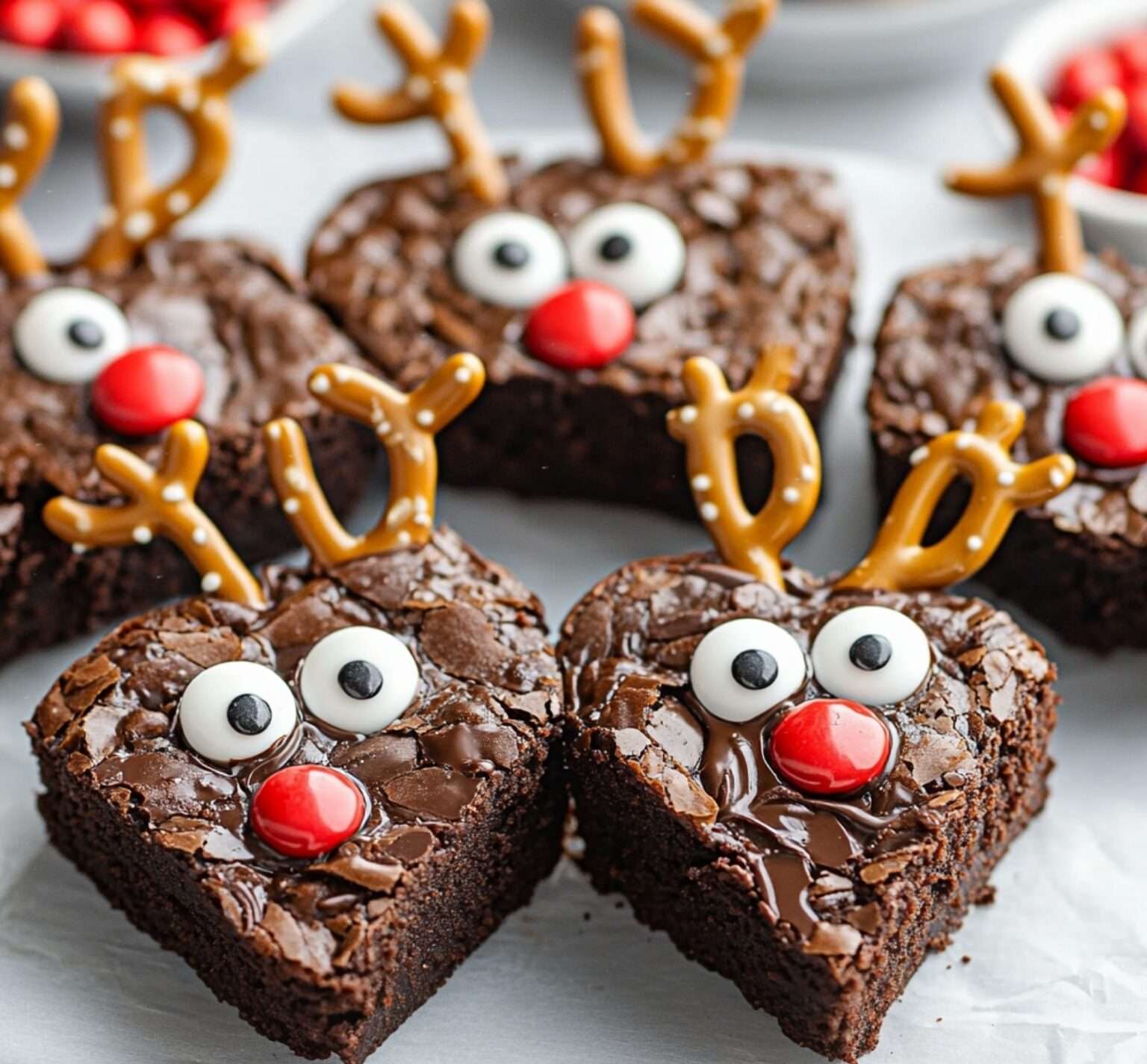 Brownies festifs en forme de rennes avec bois en bretzels, yeux en bonbons et nez rouges en Smarties, présentés sur une assiette de Noël.