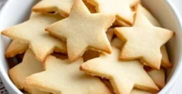 Sablés de Noël maison décorés avec du glaçage coloré et des perles en sucre, disposés sur une assiette festive.