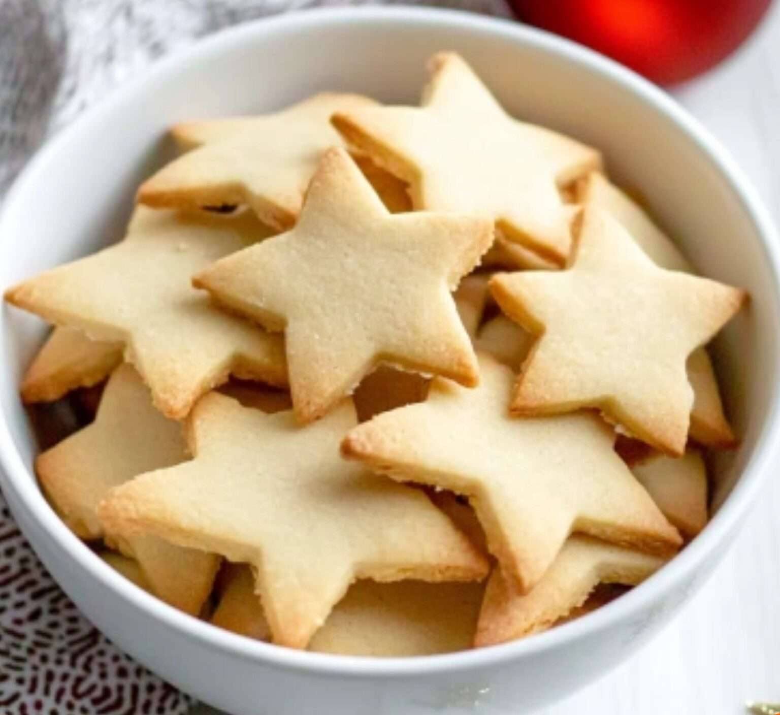 Sablés de Noël maison décorés avec du glaçage coloré et des perles en sucre, disposés sur une assiette festive.