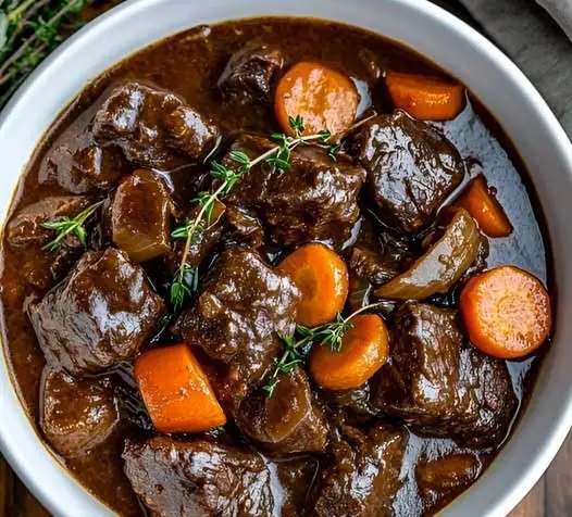 Un plat de bœuf bourguignon mijoté, servi chaud avec des légumes et un bouillon parfumé.