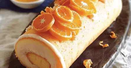 Une bûche Ensoleillée délicate et lumineuse, nappée d’un flocage orange, garnie de zestes de clémentines et posée sur une base croquante de pâte sablée.