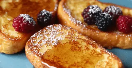 Pain perdu doré servi avec des fruits frais, sirop d'érable et une touche de chantilly.