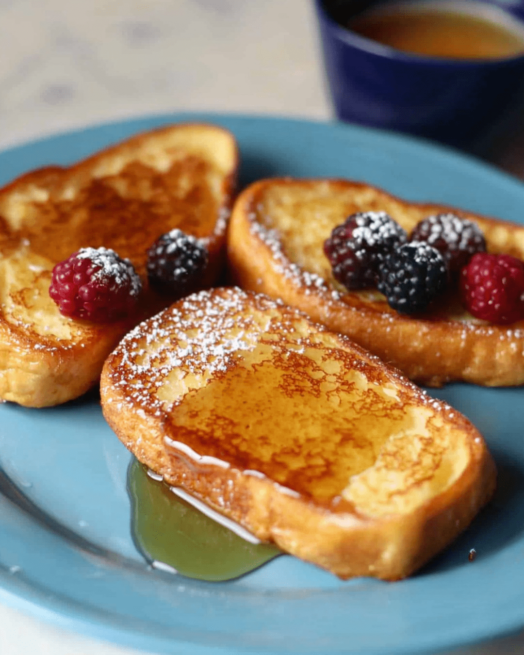 Pain perdu doré servi avec des fruits frais, sirop d'érable et une touche de chantilly.