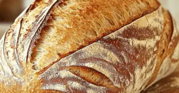 Pain rustique français doré, croustillant et fait maison, posé sur une planche en bois.