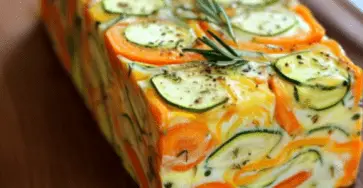 Terrine de légumes colorée, tranchée, révélant des couches de carottes, courgettes et poireaux, servie avec un coulis de tomates.