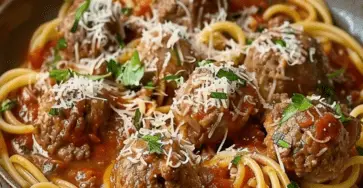 Un plat appétissant de spaghettis, nappé de sauce tomate riche et garni de boulettes de viande dorées, parsemé de parmesan frais.