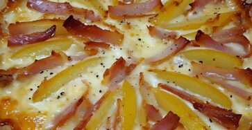 Tarte dorée avec pommes de terre, camembert fondant et lardons croustillants, servie sur une table rustique