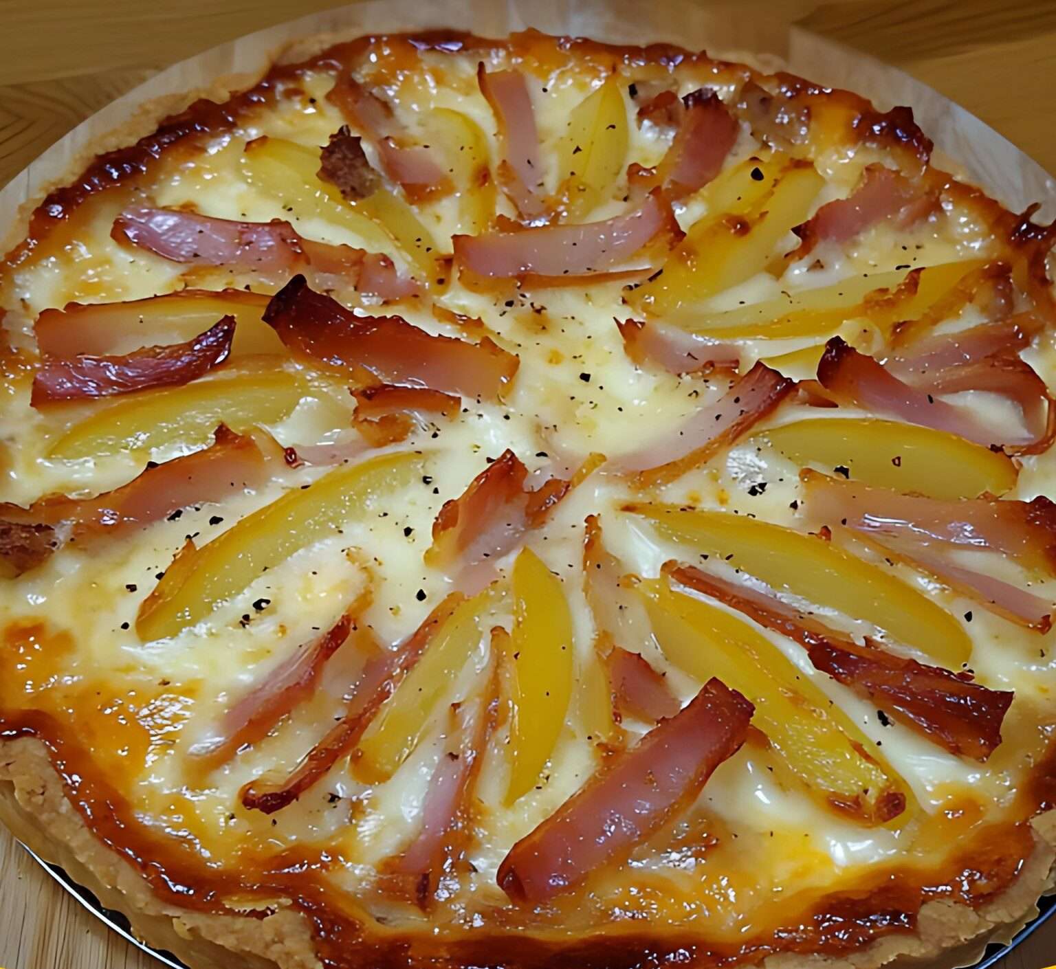 Tarte dorée avec pommes de terre, camembert fondant et lardons croustillants, servie sur une table rustique