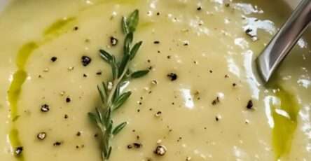 Bol de velouté de courgettes garni de feuilles de thym et d’un filet de crème fraîche