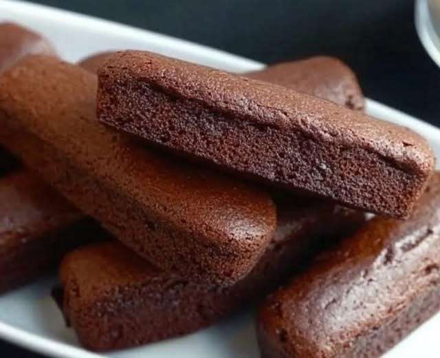 Financiers au chocolat dorés et moelleux, servis sur une assiette avec des copeaux de chocolat et une tasse de café.