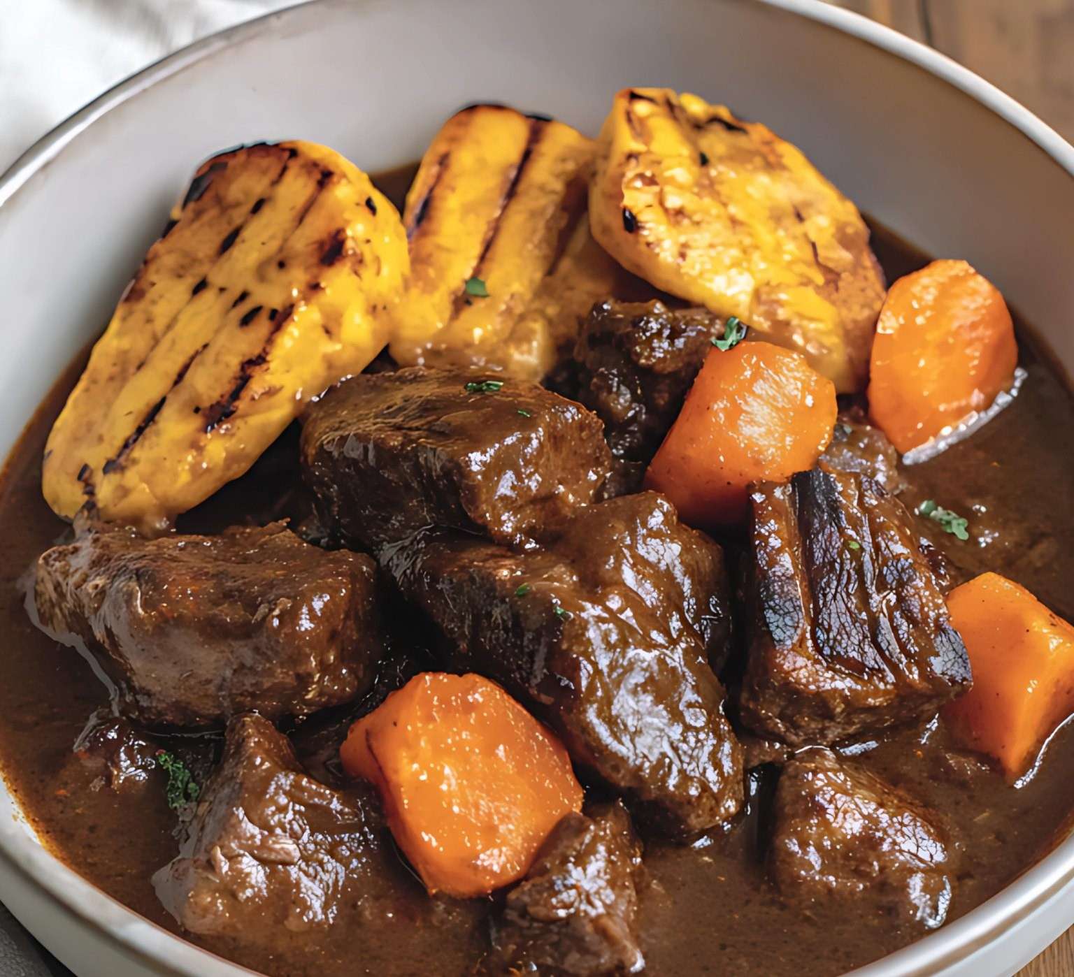 Plat de carbonade flamande traditionnelle servi avec une sauce onctueuse à la bière brune, accompagné de frites maison et garni d’herbes fraîches.