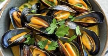 Mouclade charentaise servie dans un plat creux avec moules nappées de sauce crémeuse et pain de campagne