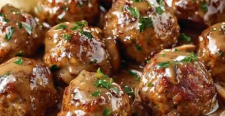 Boulettes de viande dorées servies dans une sauce crémeuse aux champignons, garnies de ciboulette fraîche et accompagnées de tagliatelles.