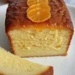 Un cake à l’orange doré, imbibé de sirop et garni de zestes d’orange et de sucre glace.