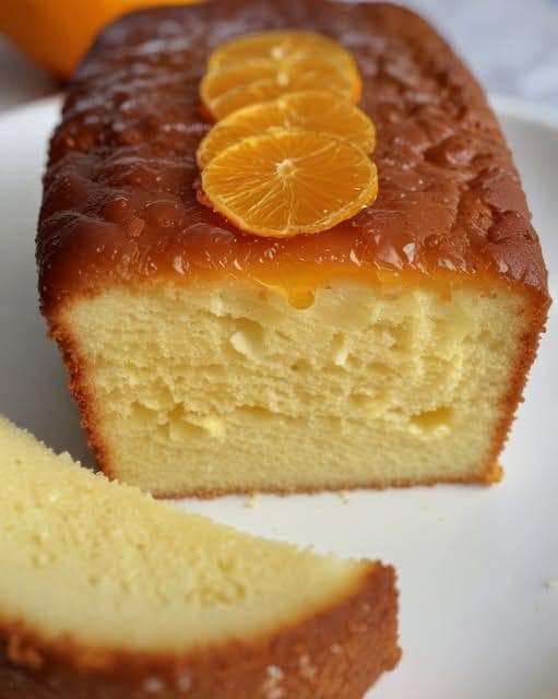 Un cake à l’orange doré, imbibé de sirop et garni de zestes d’orange et de sucre glace.