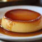 Flan au caramel doré, servi sur une assiette blanche, avec une texture lisse et un nappage brillant.