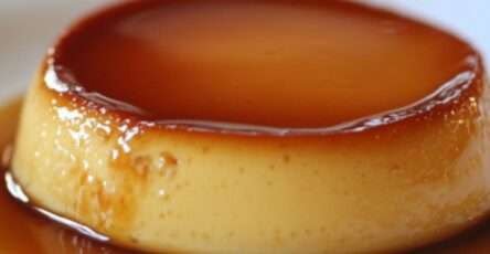 Flan au caramel doré, servi sur une assiette blanche, avec une texture lisse et un nappage brillant.