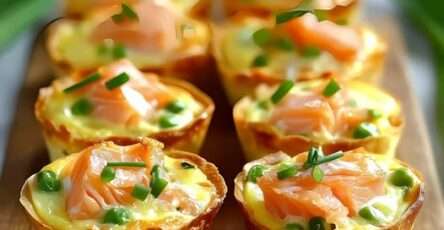 Mini quiches dorées aux poireaux et saumon fumé, décorées de ciboulette sur une assiette élégante