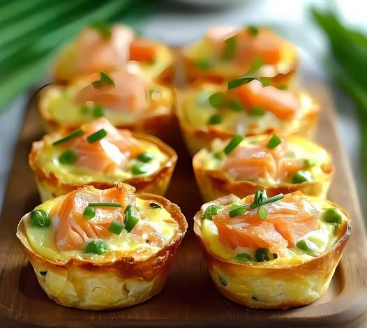 Mini quiches dorées aux poireaux et saumon fumé, décorées de ciboulette sur une assiette élégante