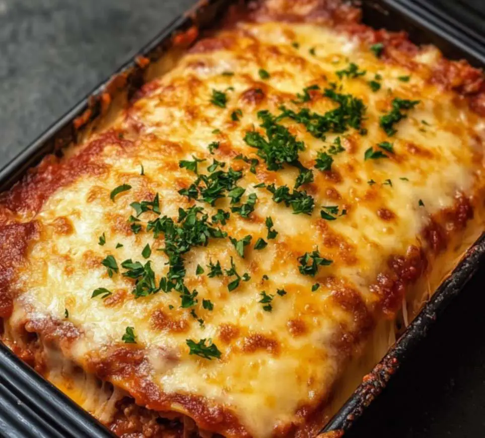 Pain de viande italien gratiné à la mozzarella, garni de basilic frais, servi sur une planche en bois