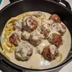 Boulettes de viande moelleuses servies avec une sauce crémeuse au roquefort, accompagnées de purée de pommes de terre et parsemées de persil frais.