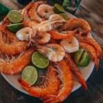 Crevettes bouillies, servies avec des quartiers de citron et de lime, garnies de persil frais.