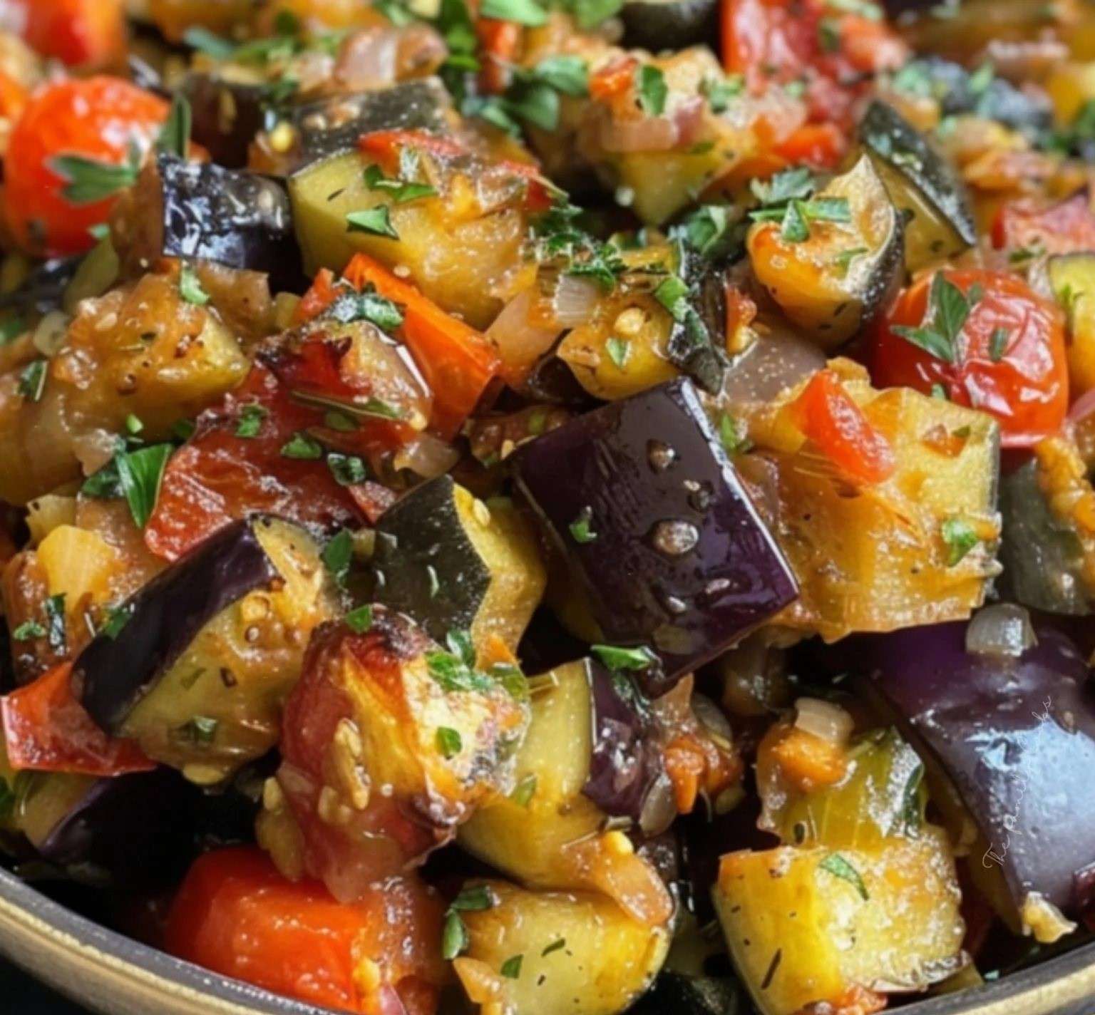 Un plat de ratatouille au four coloré, avec des légumes fondants légèrement dorés, agrémentés de fines herbes fraîches.