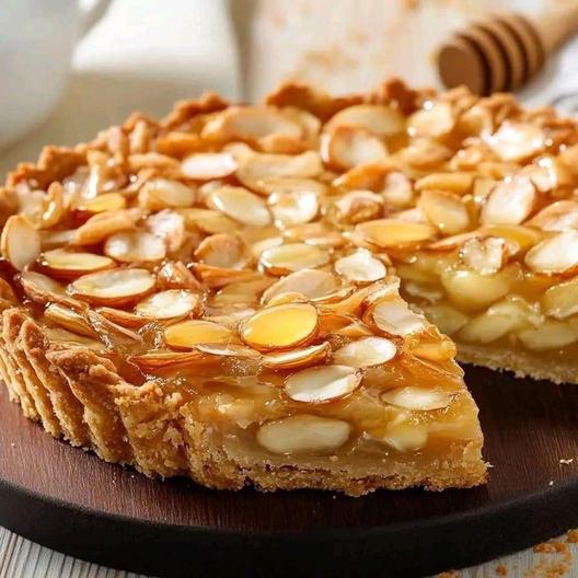 Photo d’une tarte dorée au miel et aux amandes, avec une texture croquante et une garniture fondante.