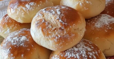 Petites brioches au yaourt dorées et moelleuses, servies sur une assiette avec un fond rustique en bois et un bol de confiture.