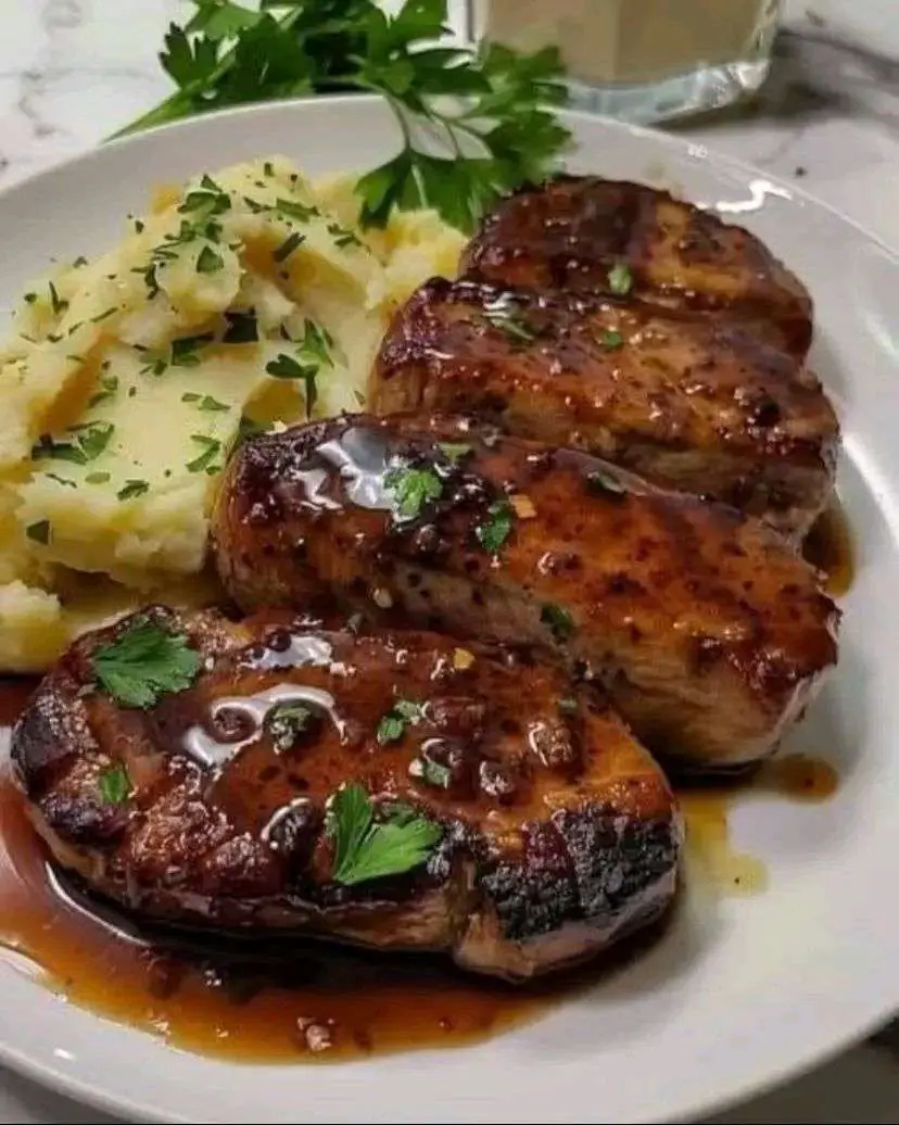 Chuletas de cerdo con miel y ajo servidas con puré de papas cremoso y perejil