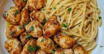 Plato de pollo con mantequilla de ajo y pasta limón parmesano servido con perejil y queso rallado