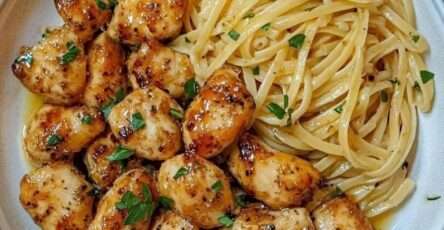 Plato de pollo con mantequilla de ajo y pasta limón parmesano servido con perejil y queso rallado
