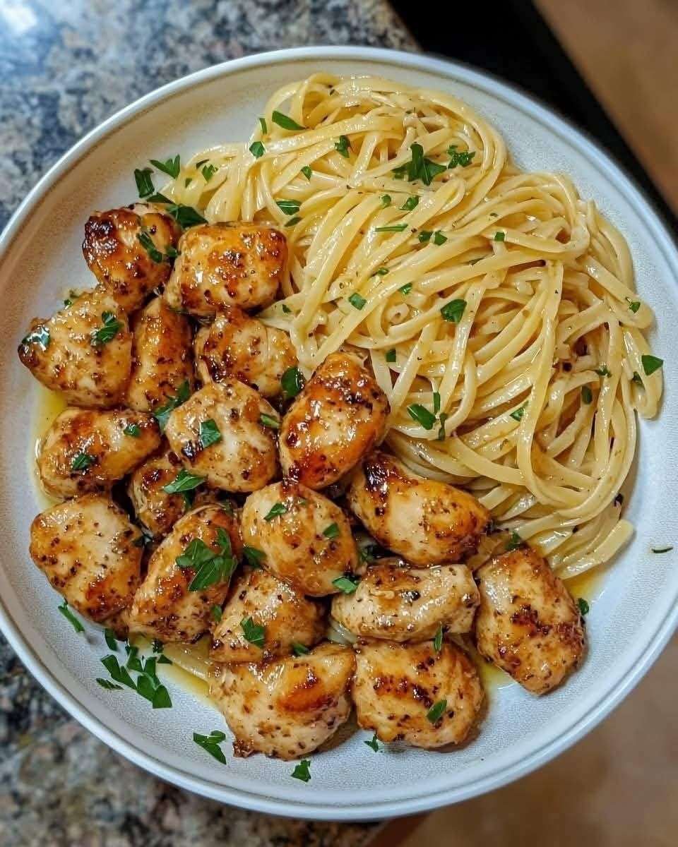 Plato de pollo con mantequilla de ajo y pasta limón parmesano servido con perejil y queso rallado