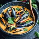 assiette de moules à la crème et curry doux servies avec coriandre fraîche et pain grillé