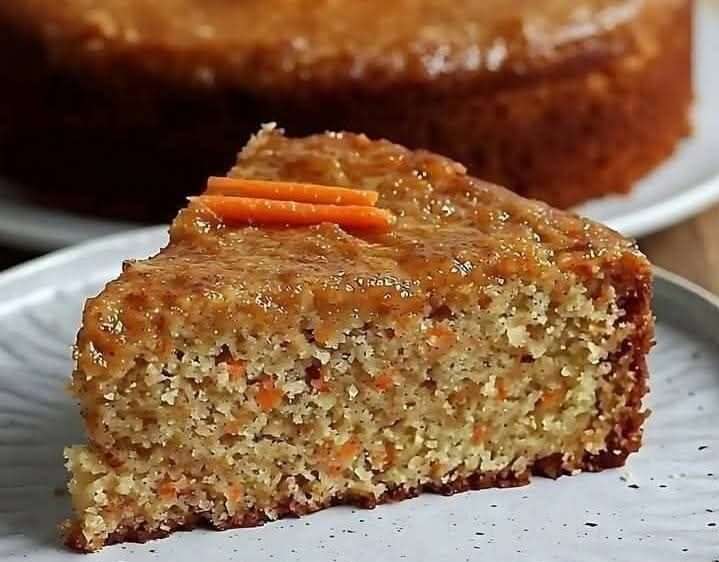 Rebanadas de torta de avena y zanahoria servidas en un plato blanco con nueces y plátano de fondo sobre una mesa rústica.