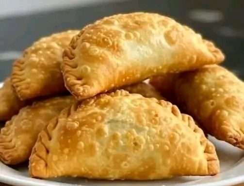 Empanadas fritas doradas rellenas de carne servidas con salsa picante