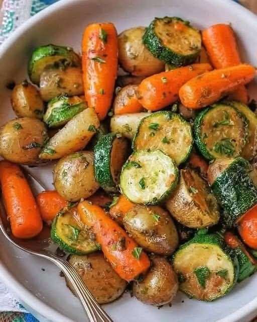 Plateau de légumes rôtis au four avec pommes de terre, carottes, courgettes, ail et herbes provençales