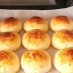 Pan de queso sin harina recién horneado, esponjoso y dorado sobre una bandeja