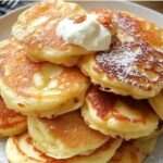 Tortitas de manzana y yogur esponjosas servidas con miel y frutas frescas en un plato blanco