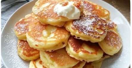 Tortitas de manzana y yogur esponjosas servidas con miel y frutas frescas en un plato blanco