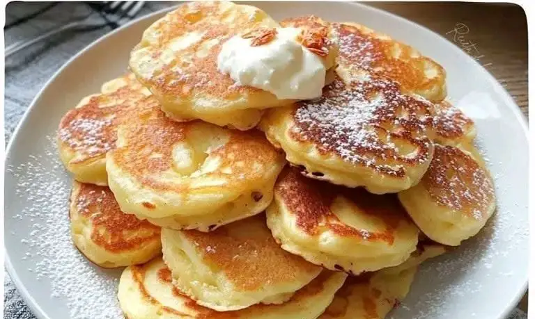 Tortitas de manzana y yogur esponjosas servidas con miel y frutas frescas en un plato blanco