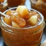 Frasco de mermelada de manzana y canela sin azúcar, con cucharita y rodajas de manzana al lado