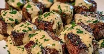 Trocitos de carne bañados en salsa cremosa de parmesano y ajo, decorados con perejil