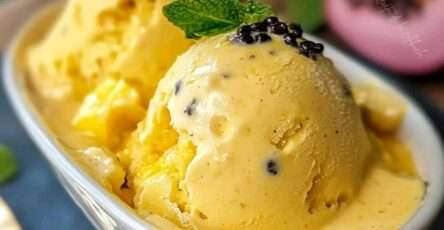 Helado de maracuyá casero servido en un bol blanco con trozos de fruta fresca encima y fondo de madera veraniega.