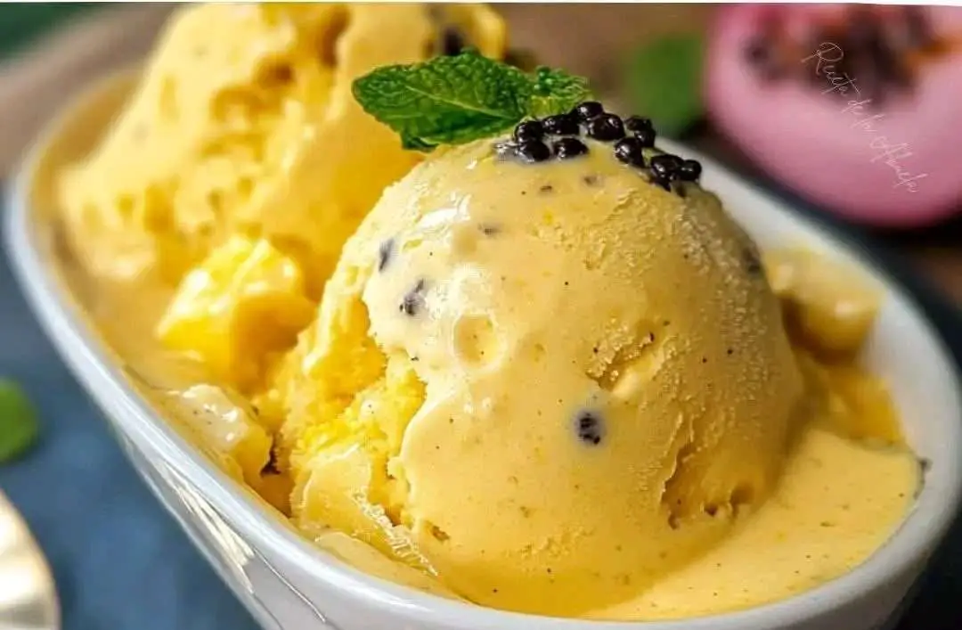 Helado de maracuyá casero servido en un bol blanco con trozos de fruta fresca encima y fondo de madera veraniega.