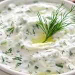 Tazón de tzatziki cremoso con pepino rallado y ramitas de eneldo