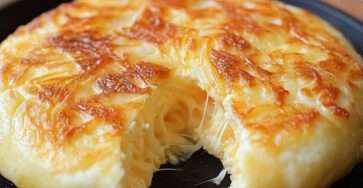 Panecillos de queso dorados cocinados en sartén, servidos sobre una tabla de madera con mantequilla derretida y queso rallado.